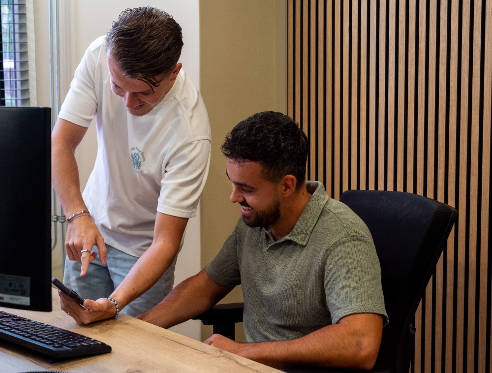 medewerker die wat laat zien op zijn mobiel aan een collega